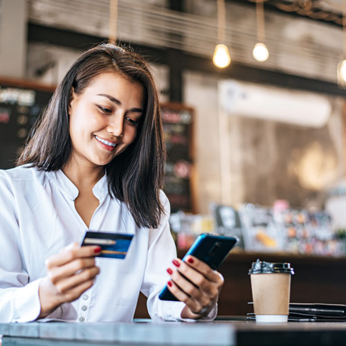 Businesswoman sitting in a cozy coffee shop, effortlessly handling her payment and breezing through the checkout process with absolute ease.