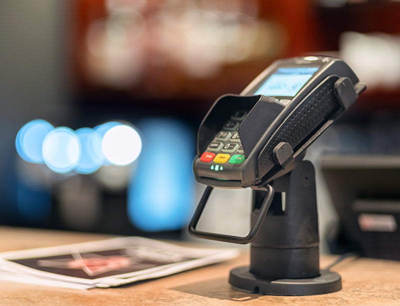 The image showcases a credit card swiping machine at a Point of Sale (POS) system.